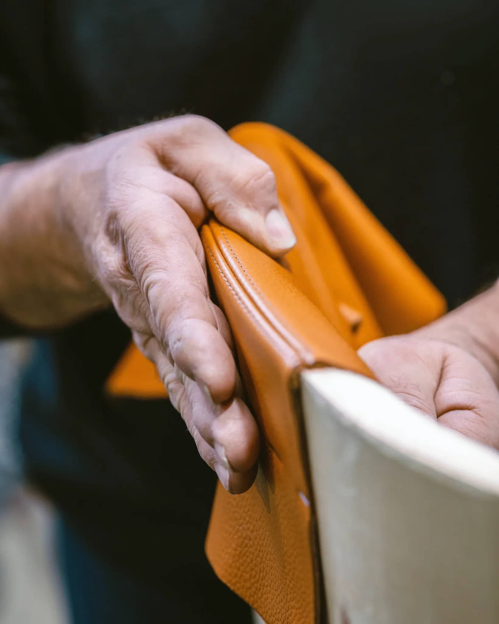 Le mani di un artigiano lavorano la pelle di una seduta